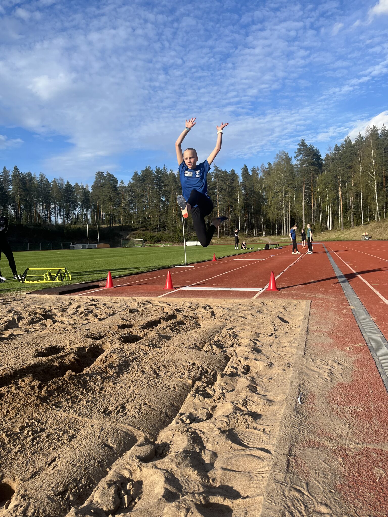 Yleisurheilija hyppäämässä pituutta yleisurheilukentällä